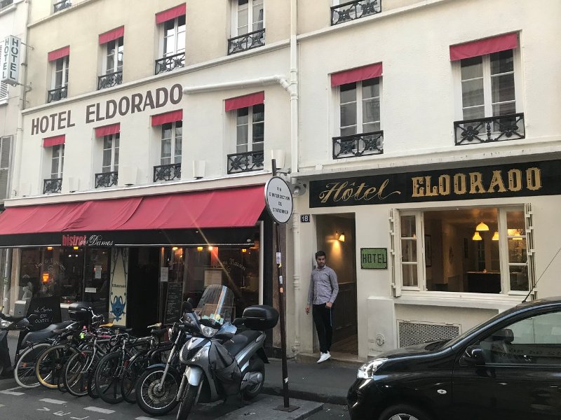 Scooter and cars parked outside Hôtel Eldorado