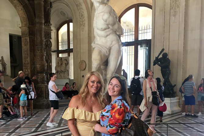 Discover the secrets of the Louvre with tourists having a photo with statue.