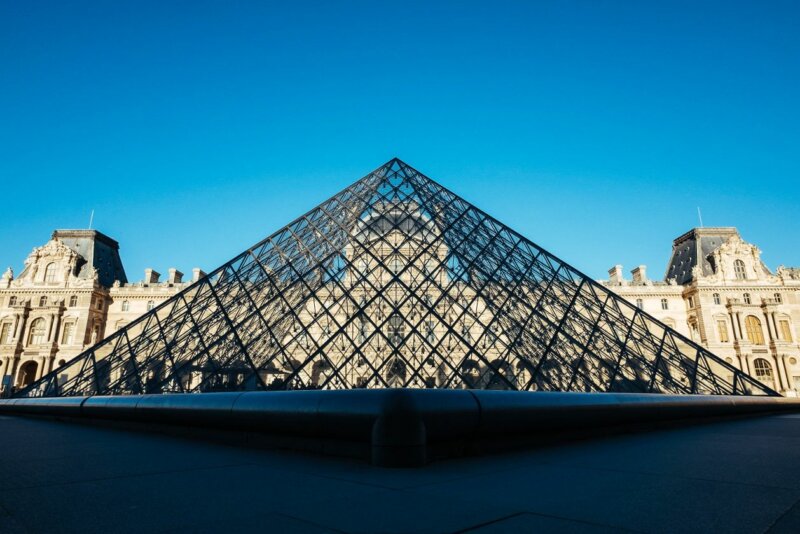 Colors and structure of the Louvre Museum clearly visible behind the Glass Pyramid 