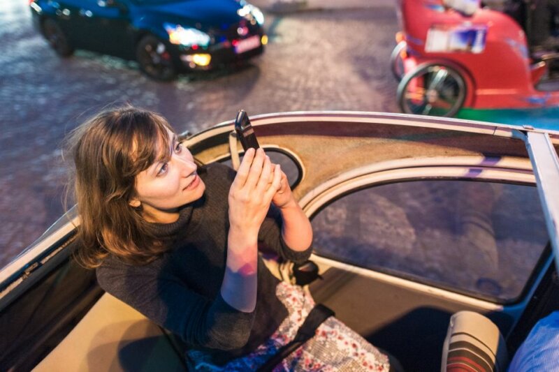 A girl on an open car taking photos while strolling in the beautiful city of Paris