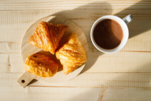 Cup of hot chocolate and croissant on wooden table