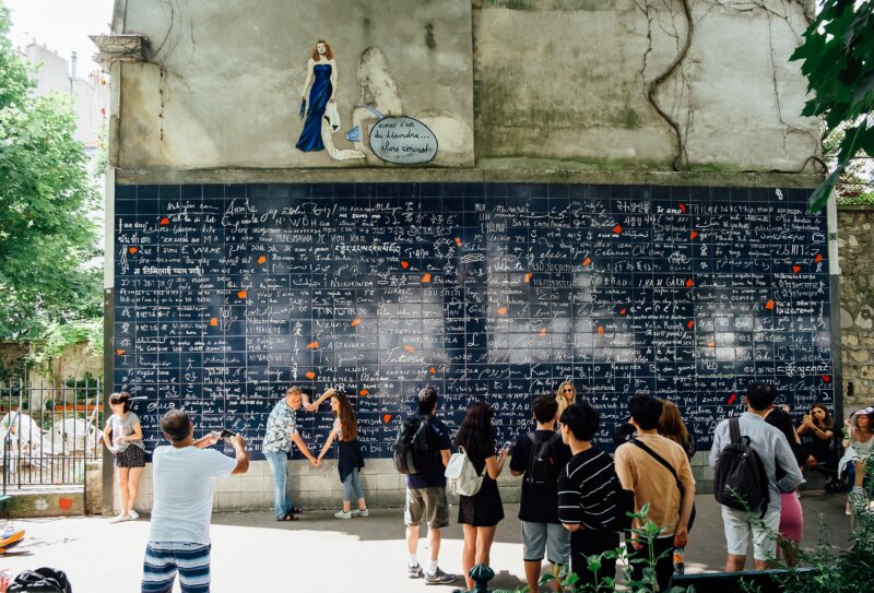 Tourists take pictures in front of the famous Le Mur des Je t'aime in Paris