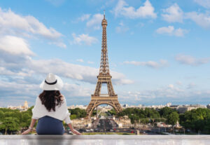 Young traveler woman in white hat looking at Eiffel tower