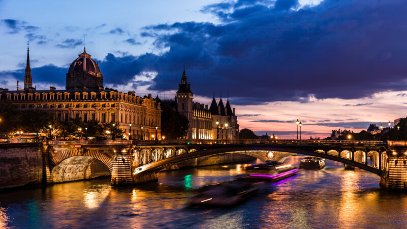 Night view of Conciergerie Castle and Pont Notre-Dame bridge over river Seine