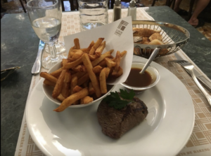 steak and fries with sauce plated at le cafe du commerce