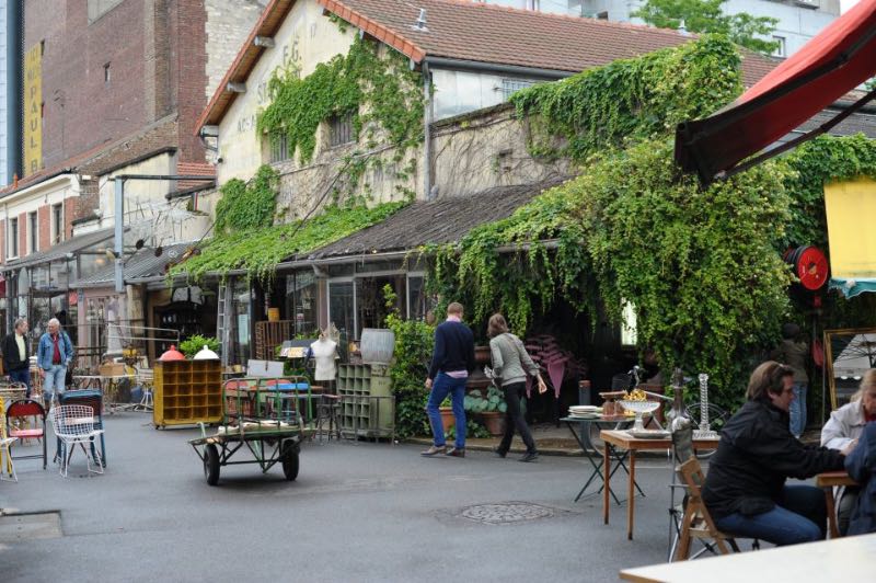 people strolling around and dining at the St. Ouen flea market in Paris