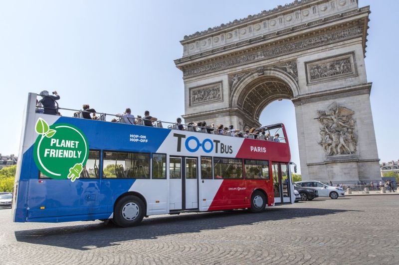 TootBus with people in the open deck in front of Arc De Triomphe