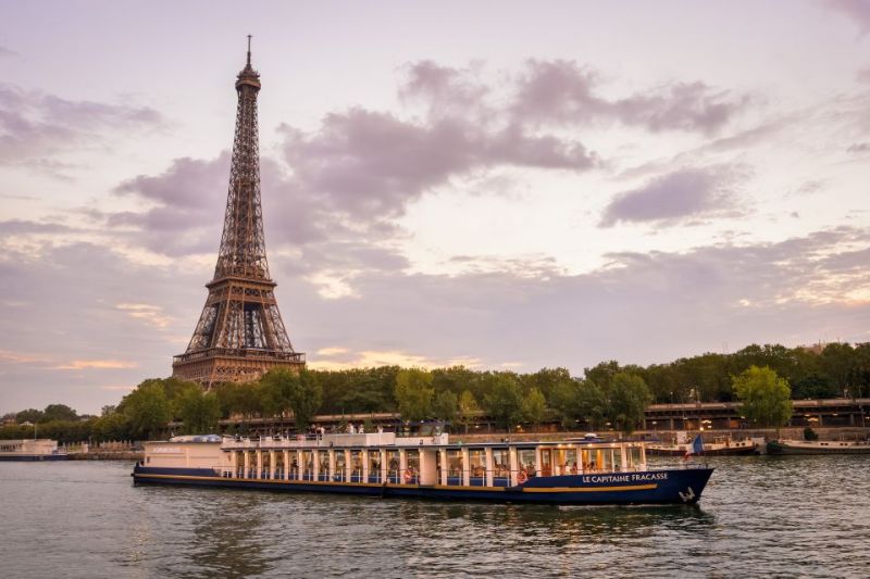 a beautiful sunset view of a cruising boat overlooking the Eiffel Tower