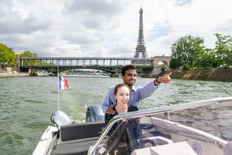 a couple enjoying a private boat tour with an overview of the Eiffel Tower at the back