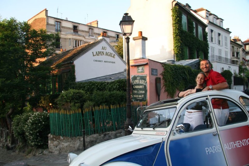 a couple riding a vintage car while touring the Paris neighborhood