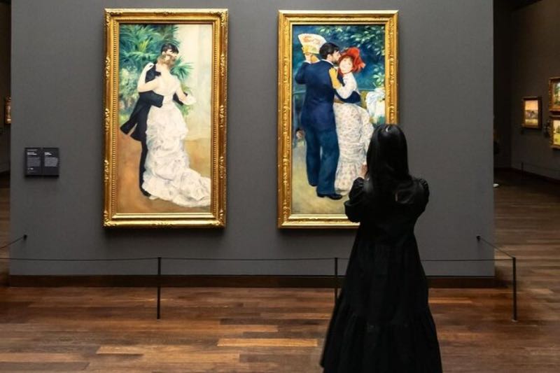 a girl tourist looking at two paintings inside a museum