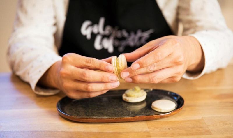 a man's hand holding a macaron