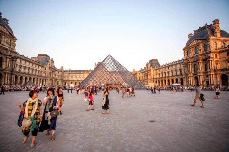 flock of tourists and a view of the Louvre Museum