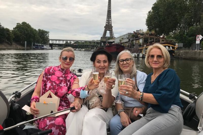 group of four women enjoying a boat tour overlooking the Eiffel Tower and a bottle of wine