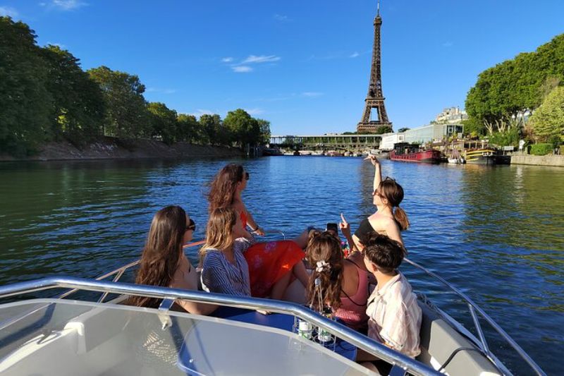 group of friends in a private boat tour in Paris enjoying the view of the Eiffel Tower