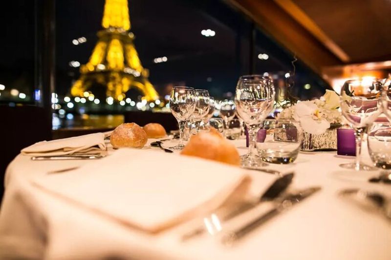 luxurious dining set up on a boat overlooking the glimmering Eiffel Tower