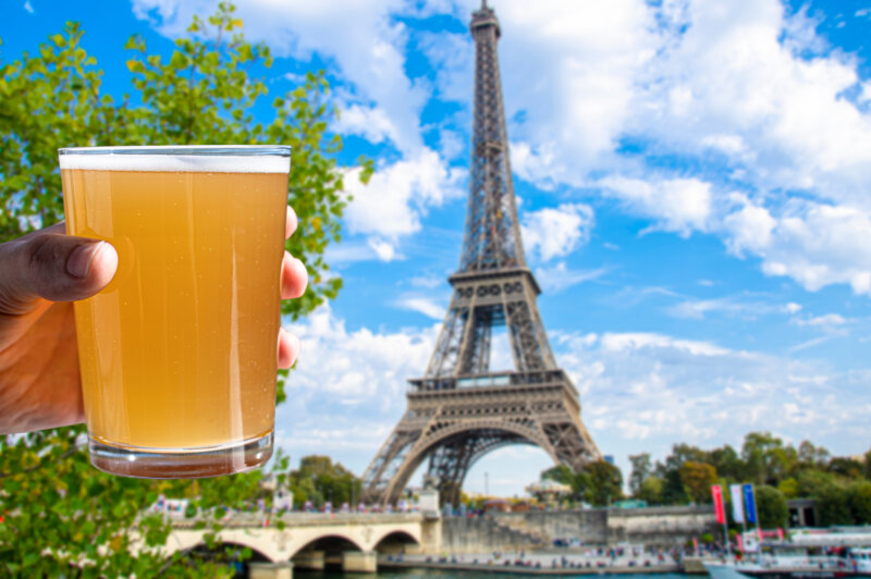 Man holding glass of light beer on Eiffel tower background, Paris France