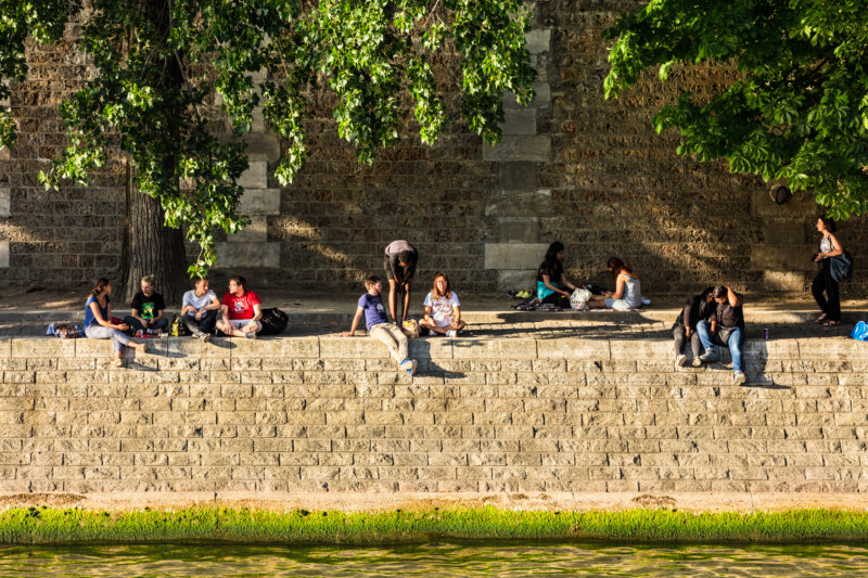 Parisians and tourists at the embankment of the Seine River in Paris at sunset