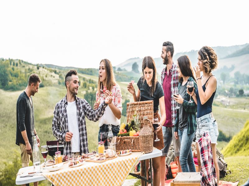 Happy adult friends eating at picnic lunch