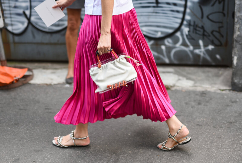 Woman wearing pink skirt, white bag and sandals walking on the streets of Milan