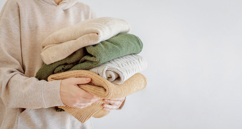 Woman's hand holding a stack of clothes 