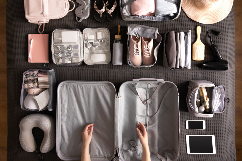 Top view woman hands getting ready to travel vacation packing suitcase use konmari method