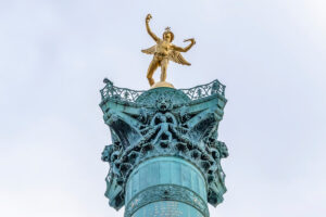 Golden Genie of Liberty statue crowning Paris July Column against overcast sky.