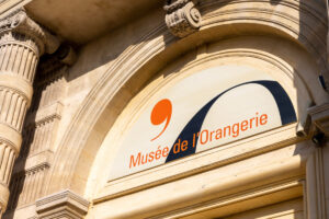 Musée de lOrangerie sign on historic Parisian building in afternoon light.