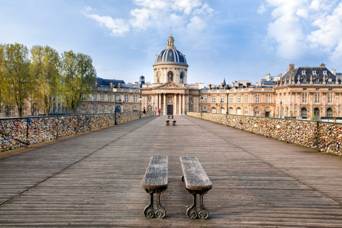 Pariss Pont des Arts with lovelocks, bench, and Institut de France backdrop.