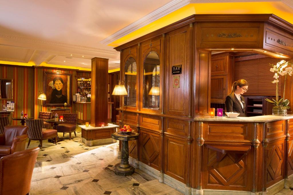 The lobby of Hôtel TROCADERO LA TOUR Best Western Premier exudes a chic ambiance, adorned with opulent furnishings and a harmonious blend of warm tones.