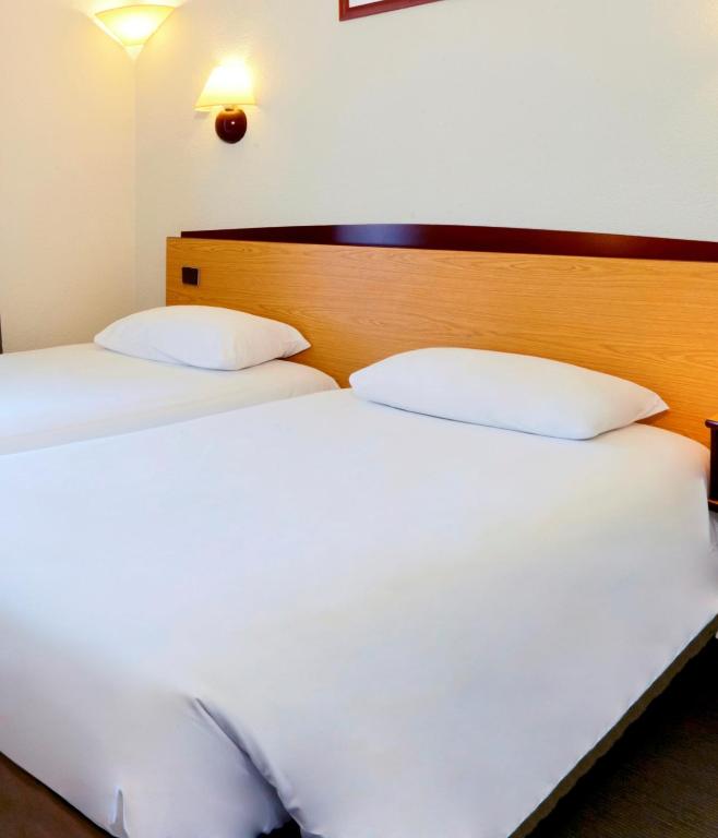 The rooms at Hôtel Campanile Paris Ouest - Boulogne boast modern amenities, featuring tasteful decor, comfortable furnishings, and large windows that allow natural light to illuminate the space.