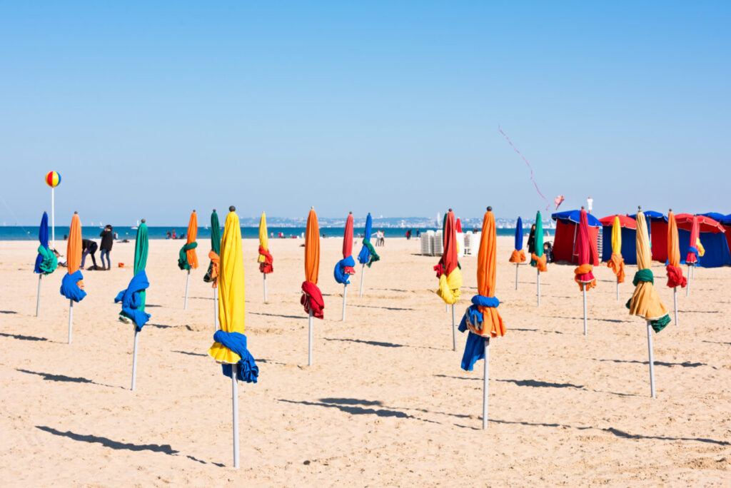 The famous colorful parasols on Deauville beach create a vibrant and iconic scene along the Normandy coast.