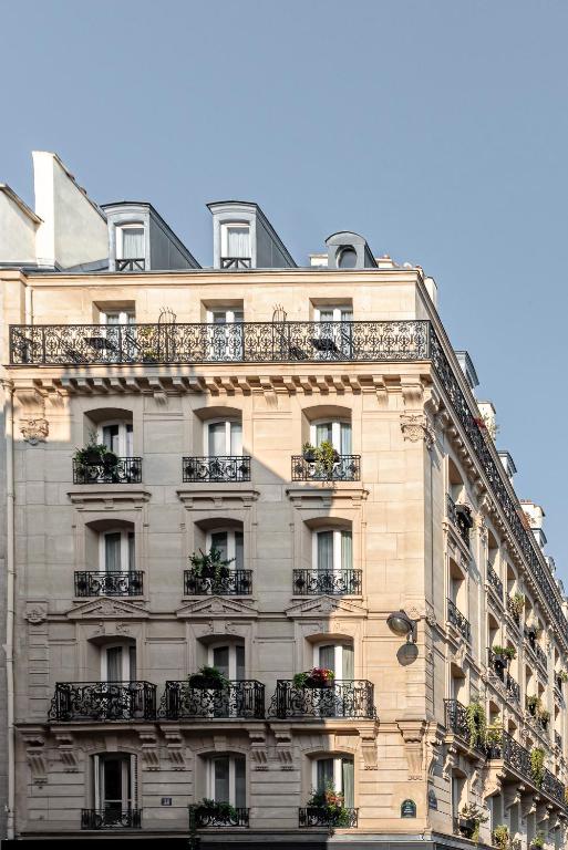 Grand Pigalle Hôtel exudes timeless elegance with its classic Parisian façade and inviting entrance, capturing the essence of refined luxury.