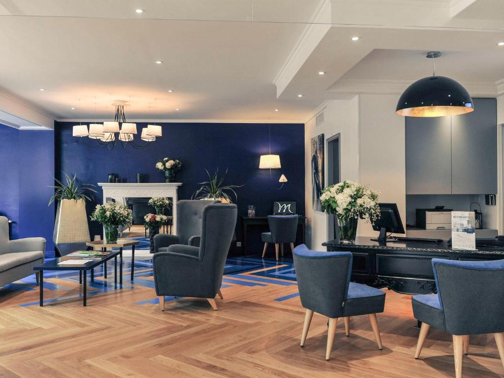 The lobby of Hôtel Mercure Paris Saint Cloud Hippodrome welcomes guests with a chic and spacious ambiance, featuring tasteful contemporary decor, plush seating arrangements, and soft ambient lighting.