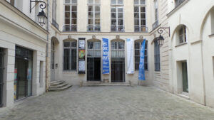 Cobblestone courtyard with banners in Paris building.