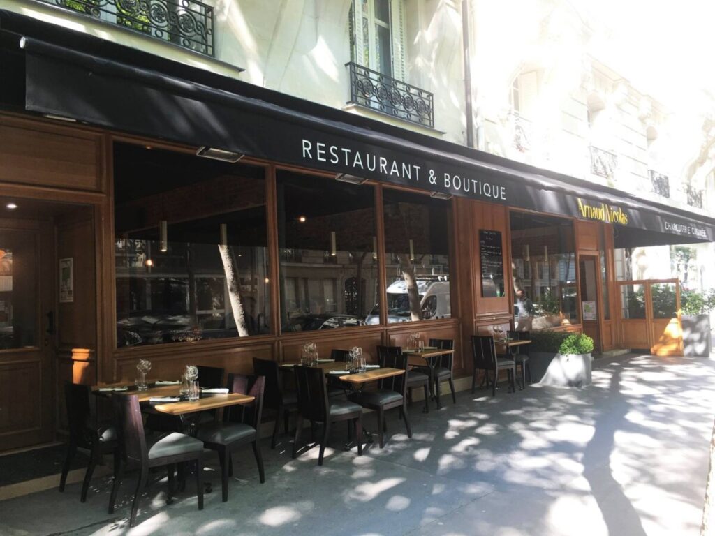 Exterior view of Arnaud Nicolas restaurant in Paris, featuring tables and seats set up outside for dining