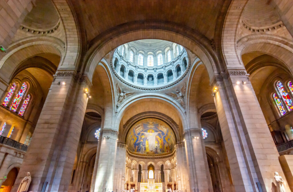 Interior view of the Basilica of Sacre Coeur, showcasing ornate mosaics, arches, and a grand dome in Paris, France.