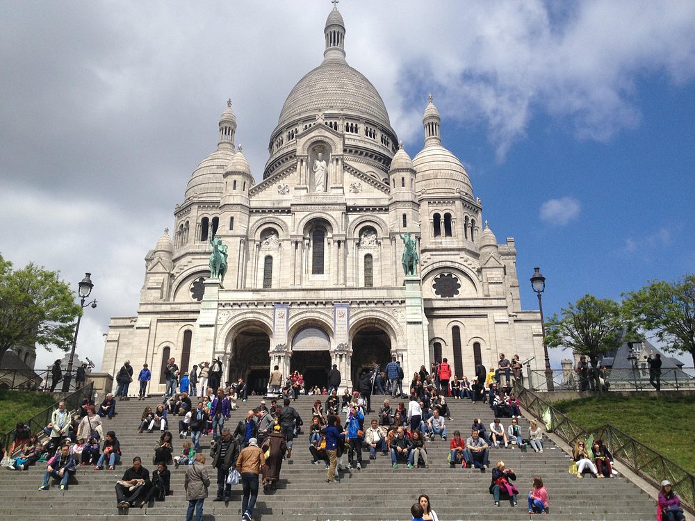 Many people gathered on the steps of the Basilique du Sacré-Cœur de Montmartre, socializing and taking in the surroundings.