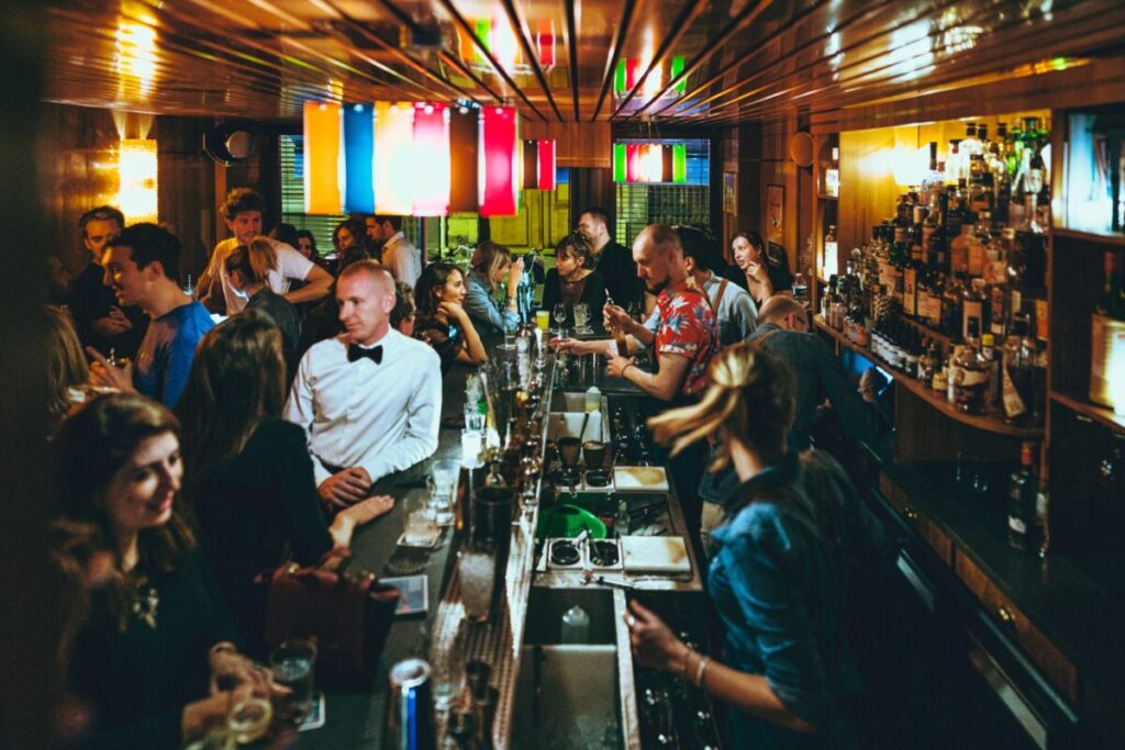 Inside Bluebird bar in Paris, a lively scene with numerous people seated at the bar, socializing and enjoying their time.