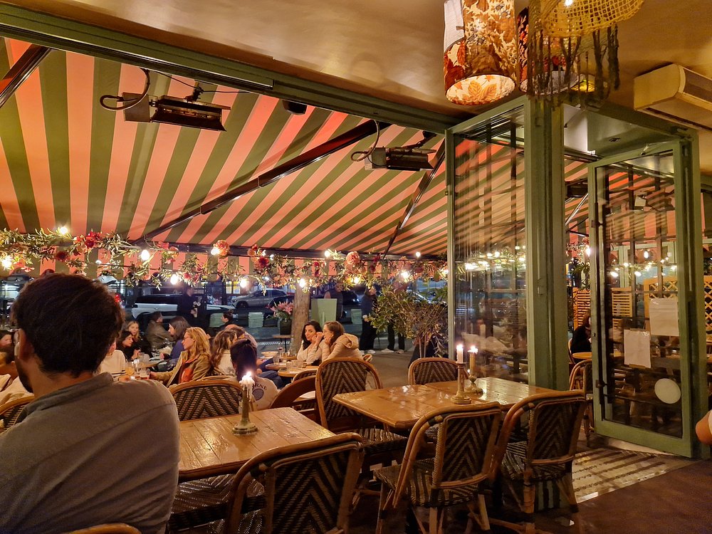 Patrons seated at tables in the outdoor section of Café Bohème, a popular restaurant in Montparnasse, Paris.
