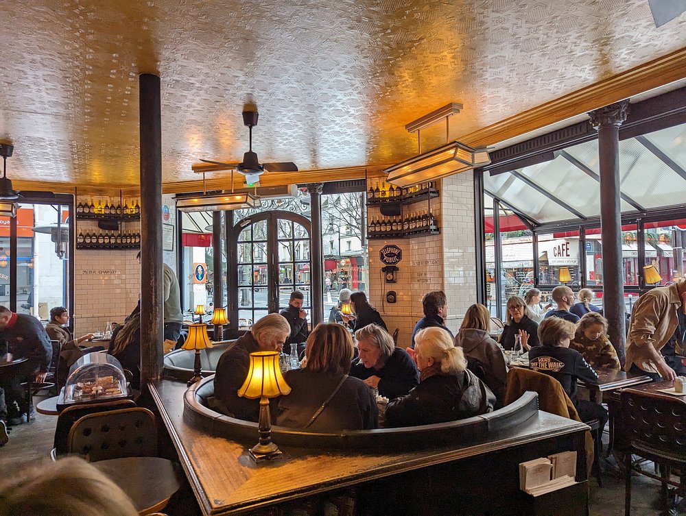 Bustling Café Charlot in Paris, featuring patrons at tables and a ceiling fan overhead.
