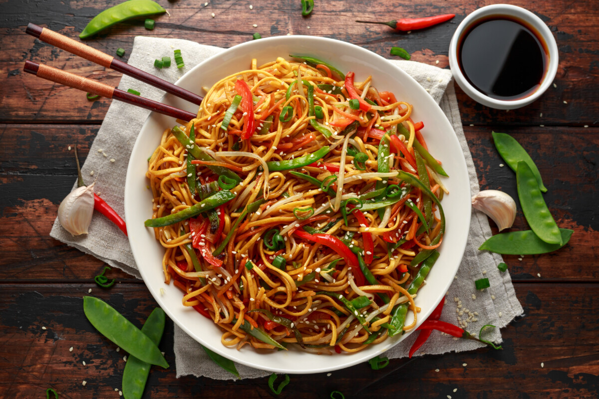 Chow mein, noodles and vegetables dish with wooden chopsticks