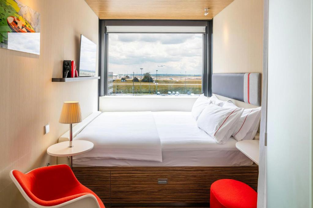 Cozy bedroom in CitizenM Paris Charles de Gaulle Airport with a bed and a chair for relaxation.