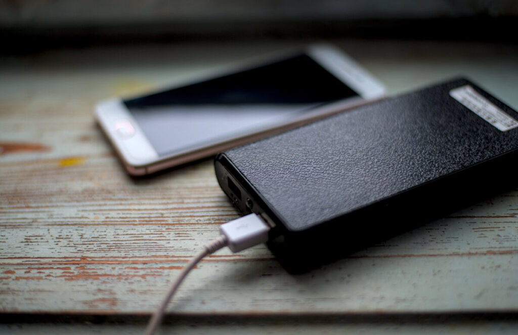 Close-up of a power bank charging a mobile device on a table, showcasing its sleek design and functionality.