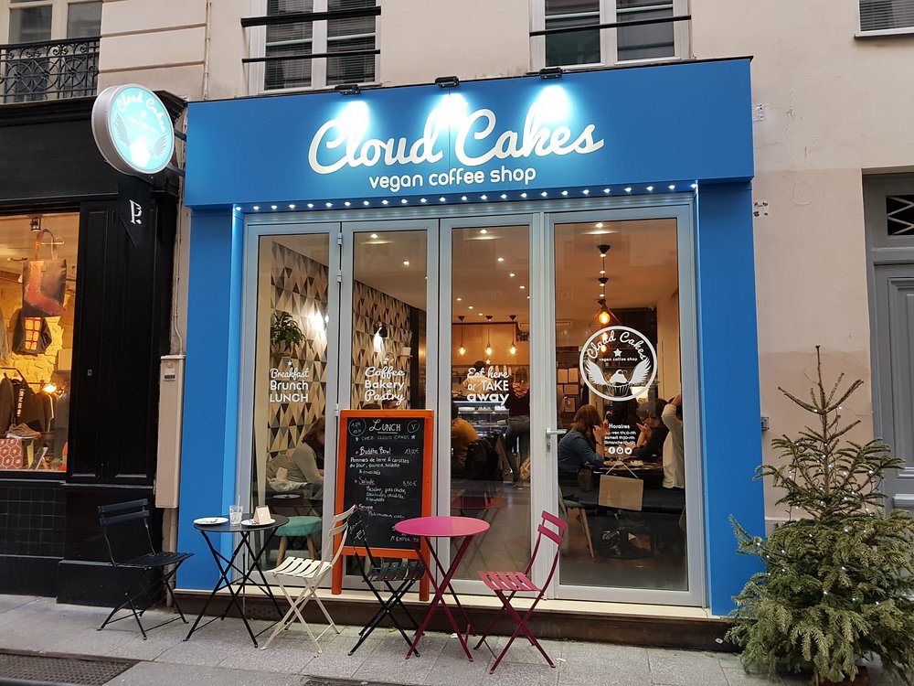 Cloud Cakes café in Paris, showcasing blue and white decor with outdoor seating arrangements of tables and chairs.