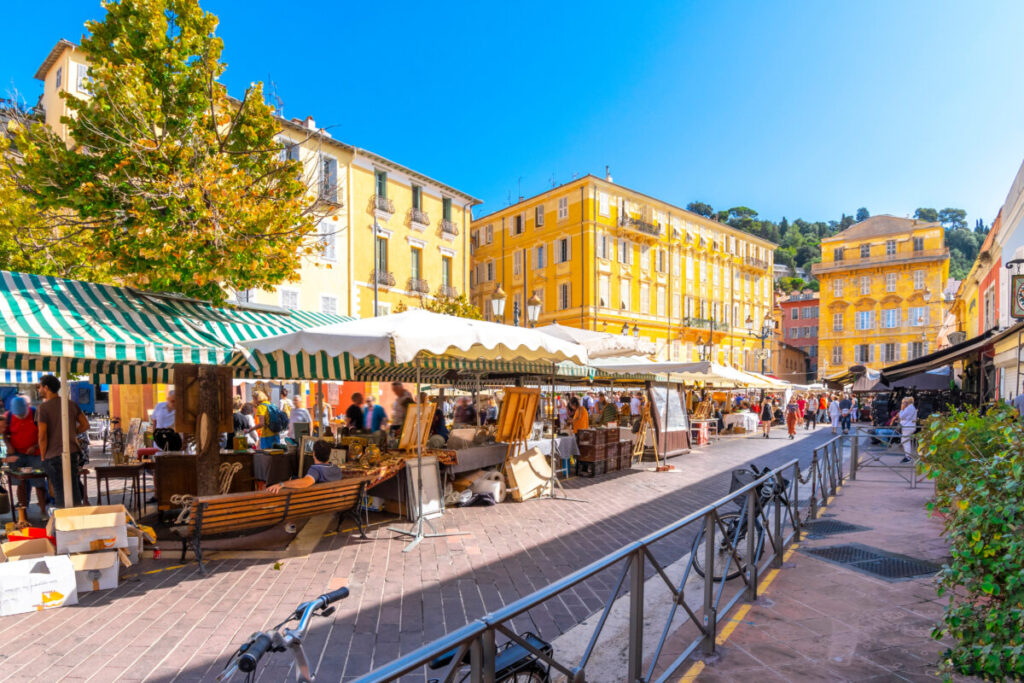 Vibrant Cours Saleya market in Vieux Nice, bustling with colorful stalls on a sunny summer day along the Cote d'Azur.
