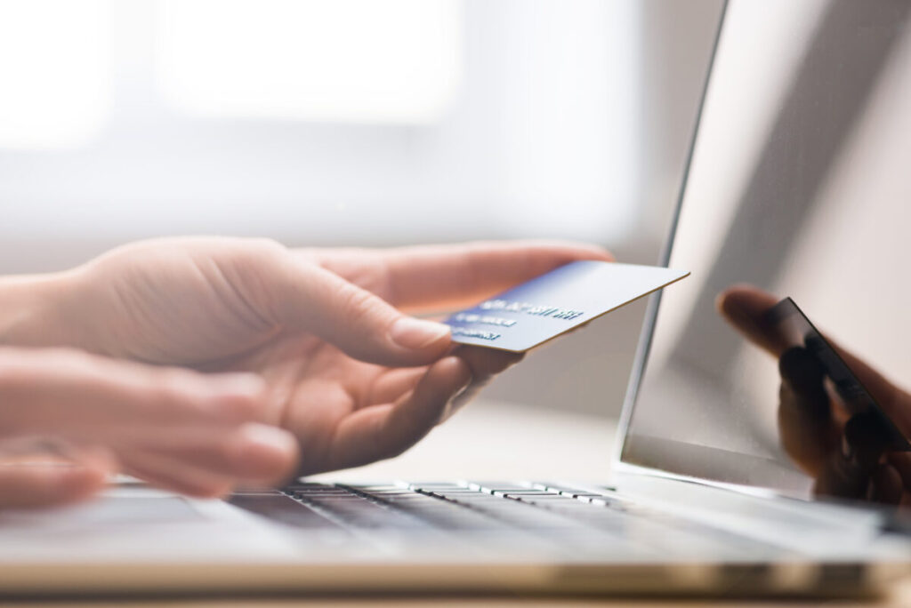 Close-up of a hand holding credit card near to a laptop