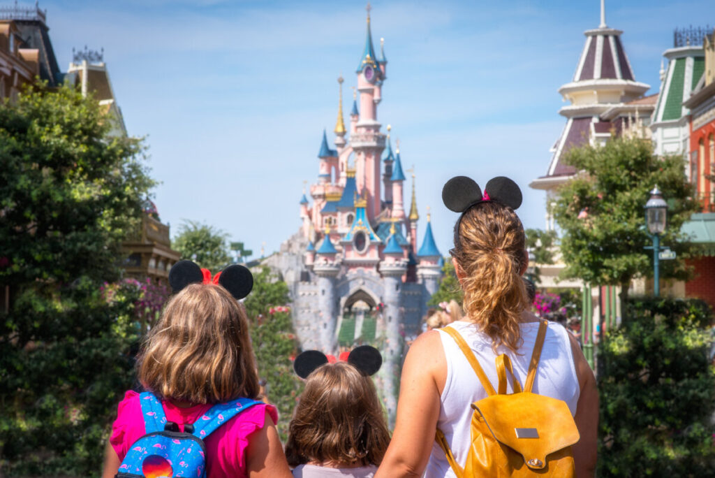 Mother and her daughters look up at the majestic Princess Castle, enjoying their visit to Disneyland Paris park.