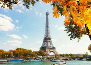 Eiffel Tower over the Seine River, framed by autumn trees, showcasing a picturesque view of Paris in fall.