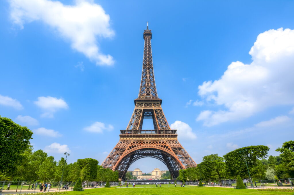The Eiffel Tower stands tall over the Field of Mars, showcasing the beauty of Paris, France, under a clear blue sky